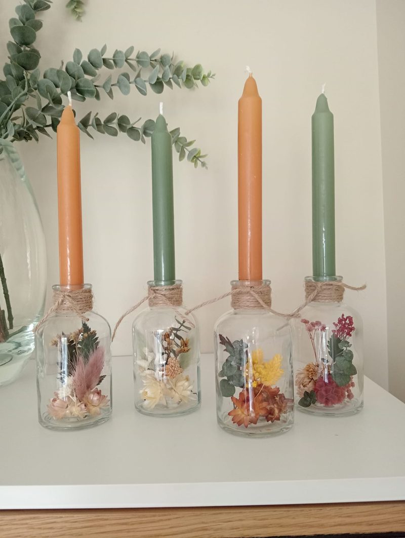 Centros de mesa con velas y flor preservada en botellas de cristal